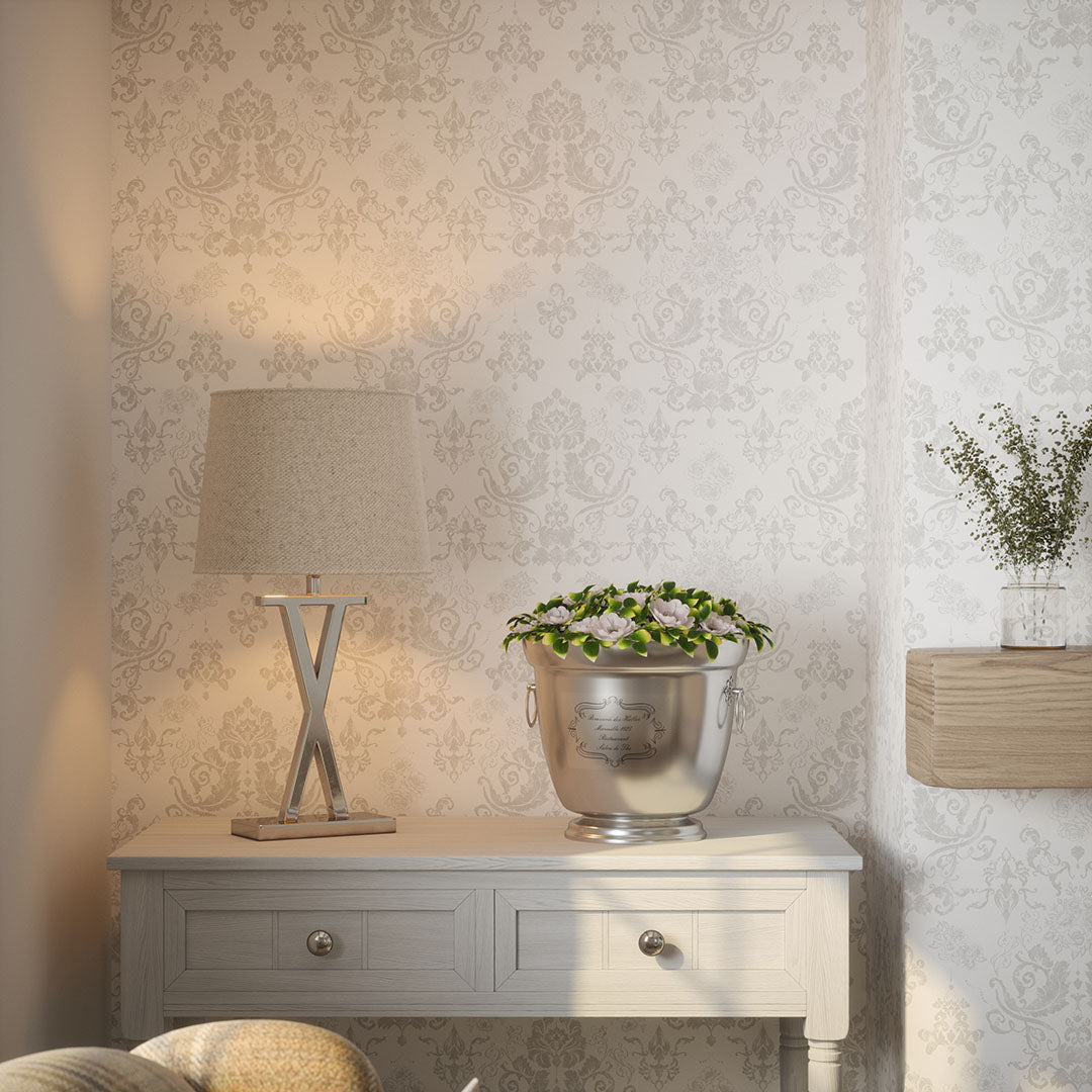 Living room nook with table, lamp, and metallic vase against a grey damask wallpaper featuring floral motifs.