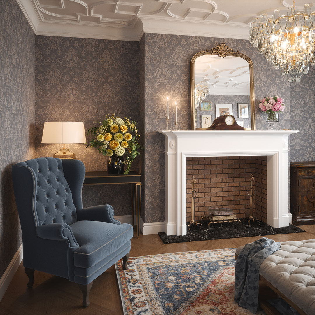 Townhouse living room setting with a fireplace, chandelier, and a blue suede grandpa chair. The walls feature a damask wallpaper in slate grey with light grey floral motifs.