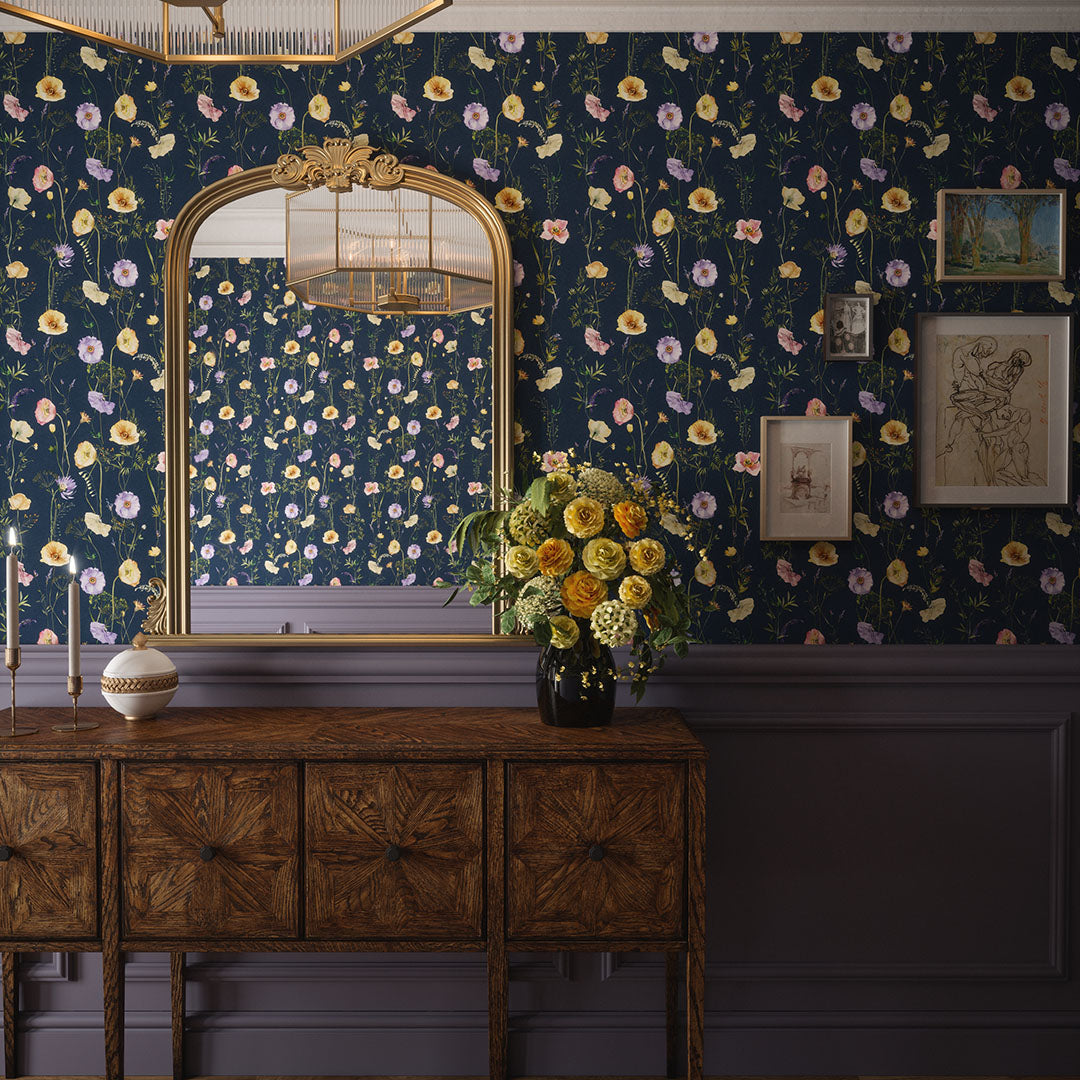Townhouse hallway setting with panelled walls, wooden drawers, and navy wallpaper featuring various pastel florals. 
