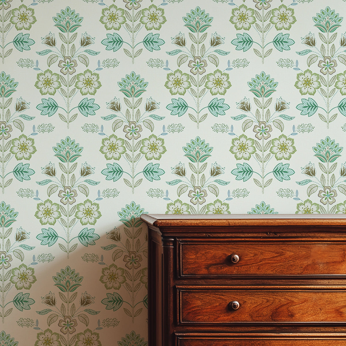 Floral wallpaper with green patterns on a wall next to a wooden dresser.