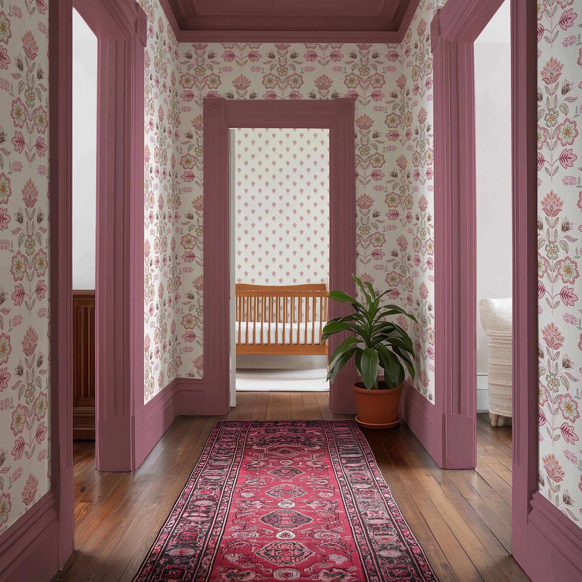 Decorative hallway with pink floral wallpaper, a red rug, and a plant.