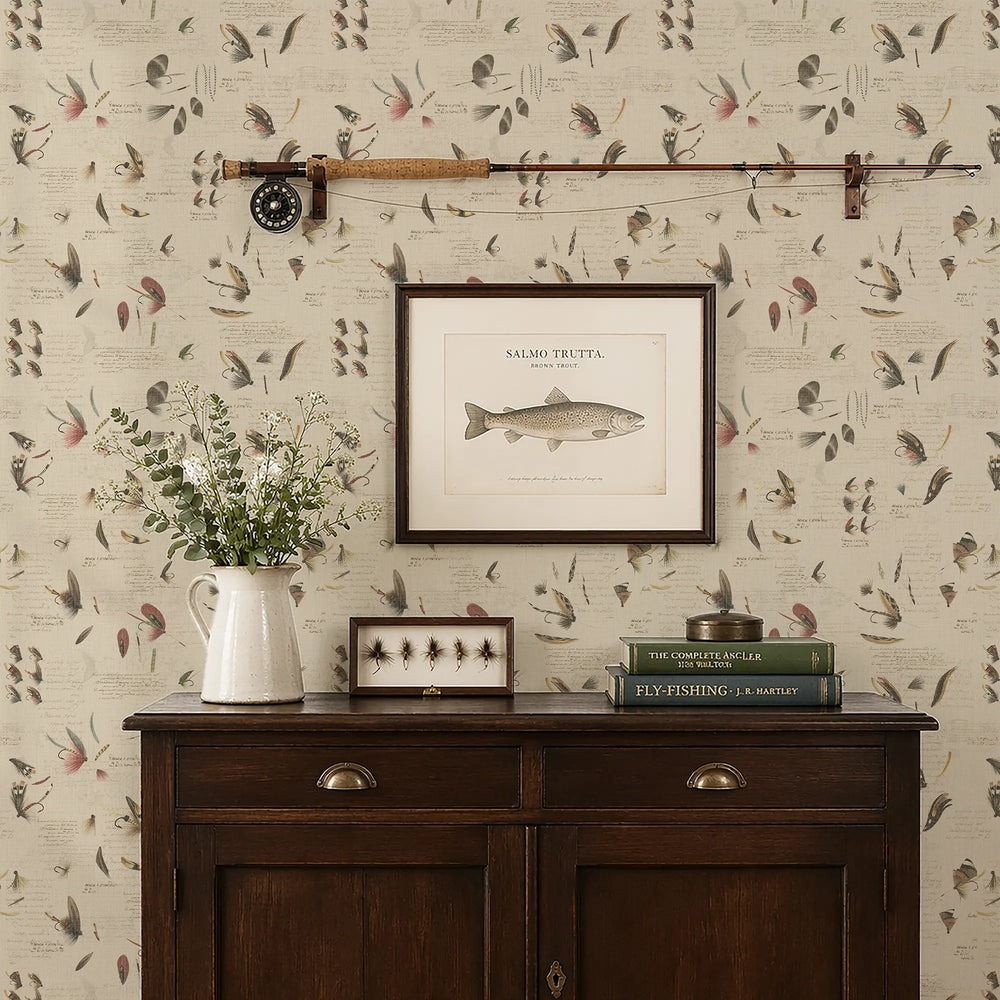 Wall with decorative wallpaper featuring fishing themed design, a wooden sideboard with books and a vase, and framed pictures.
