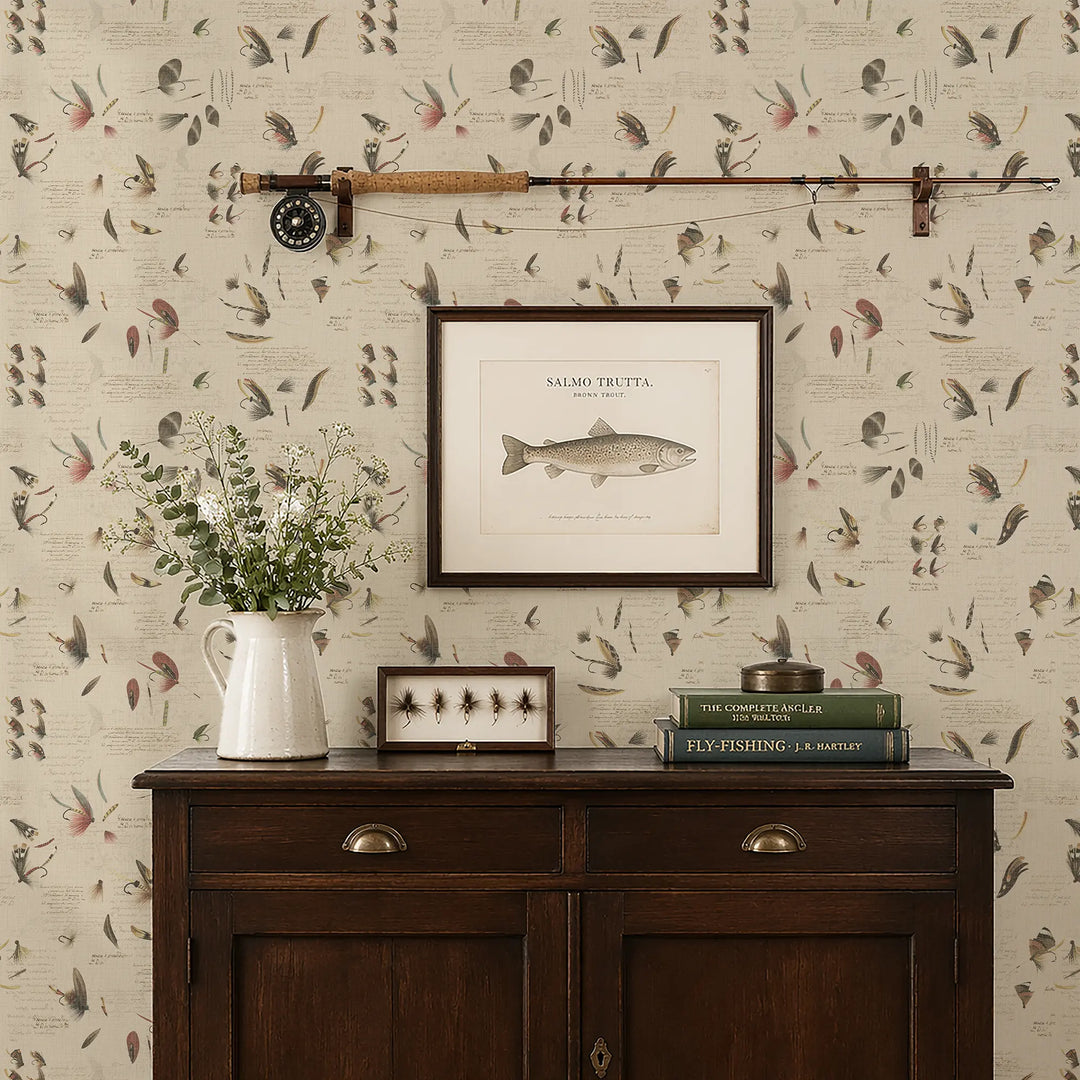 Wall with decorative wallpaper featuring fishing themed design, a wooden sideboard with books and a vase, and framed pictures.