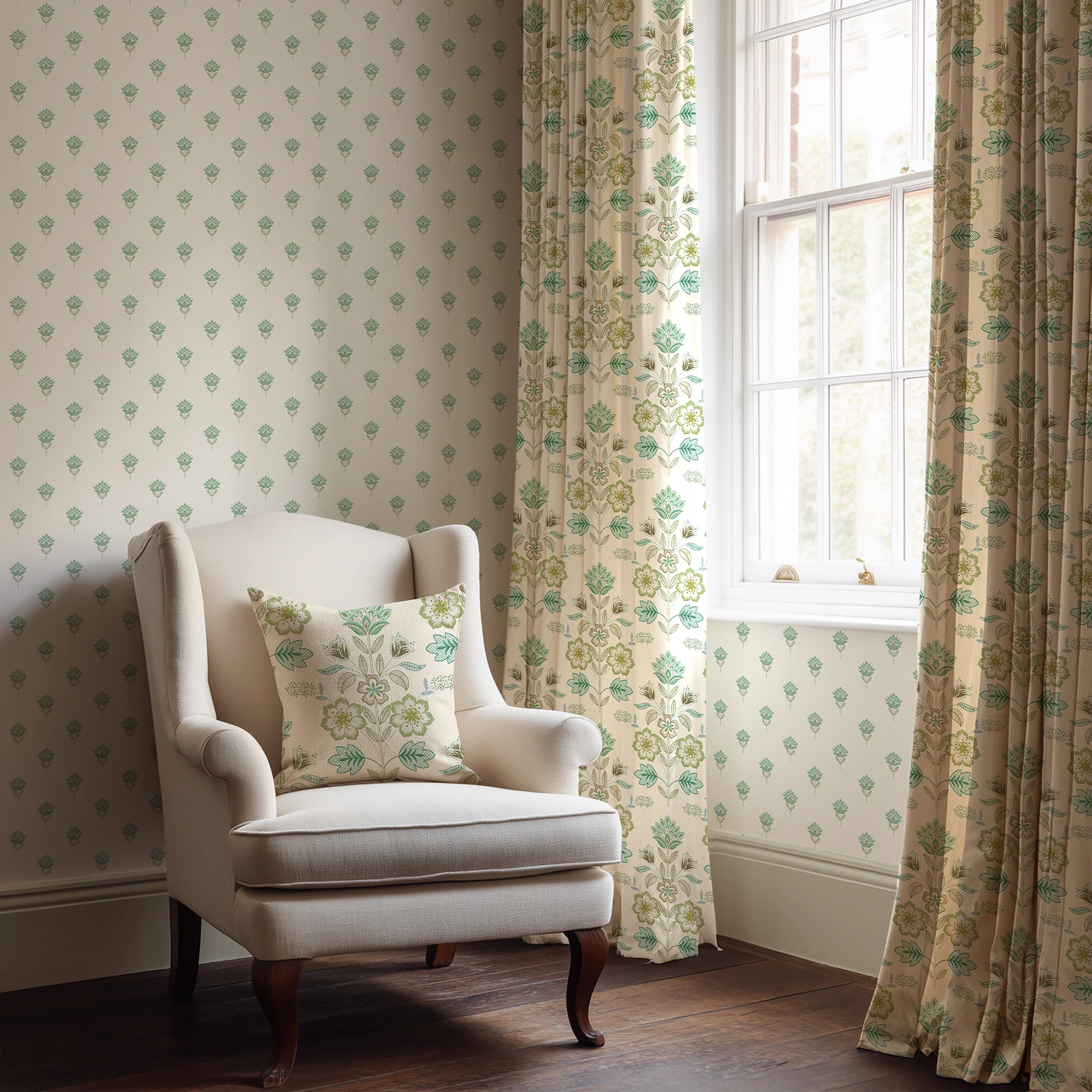 White armchair with a patterned pillow in a room with floral curtains and wallpaper in greens and blues.