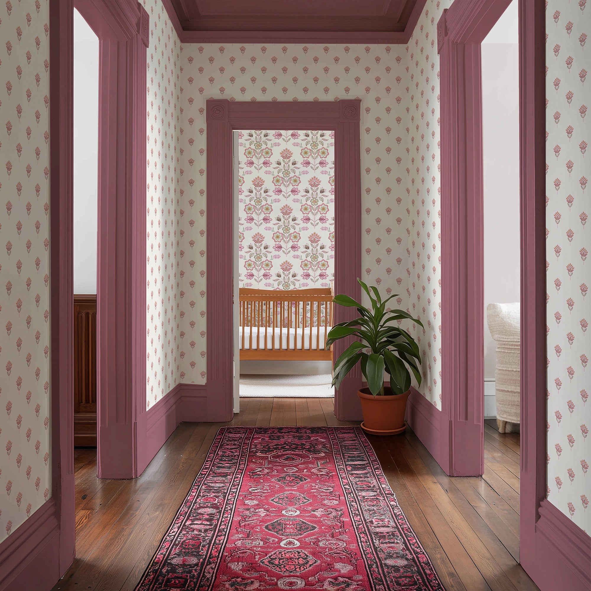 Decorative hallway with pink, floral-patterned wallpaper, pink doors, and a red rug.