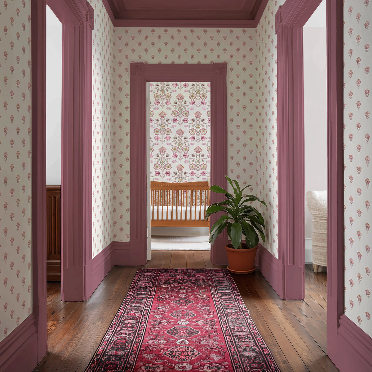 Decorative hallway with pink, floral-patterned wallpaper, pink doors, and a red rug.