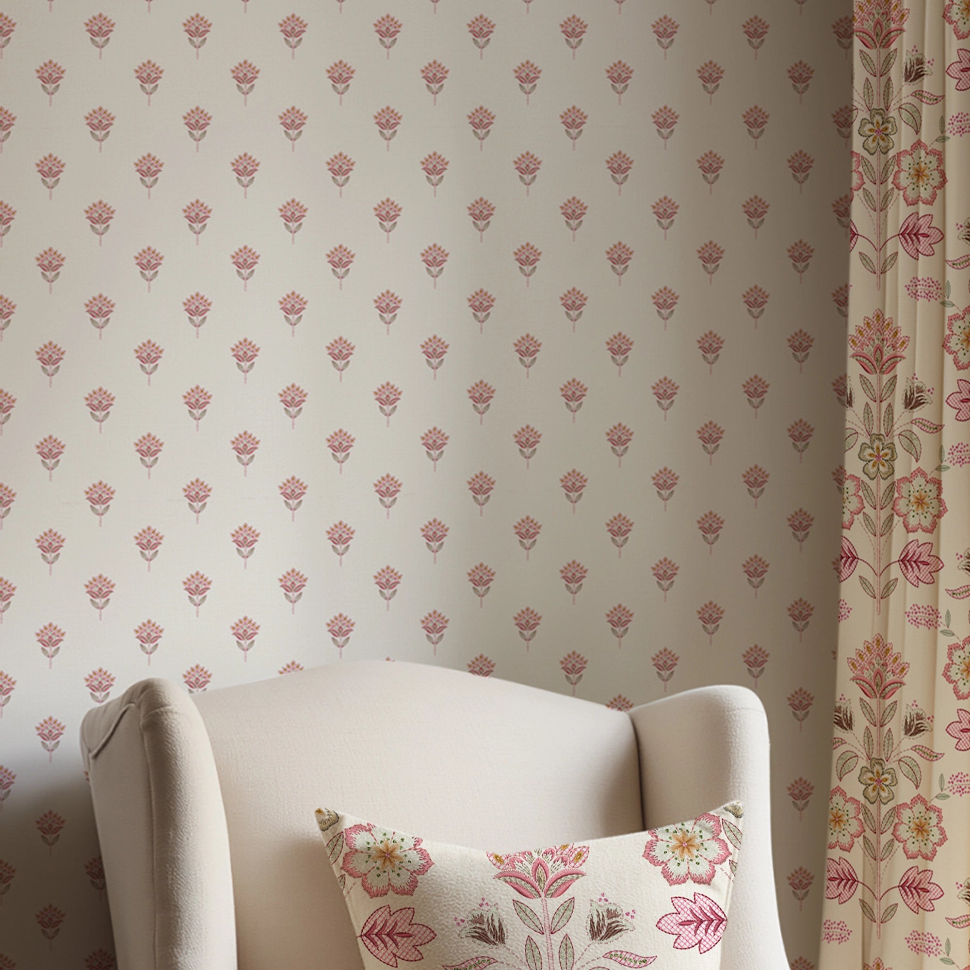 White armchair with floral pillow against a small, floral-patterned wall.